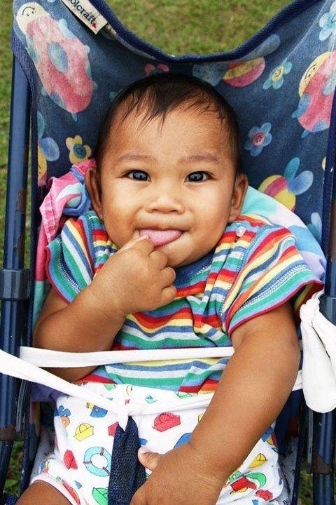 Baby wearing colorful clothes in a stroller.