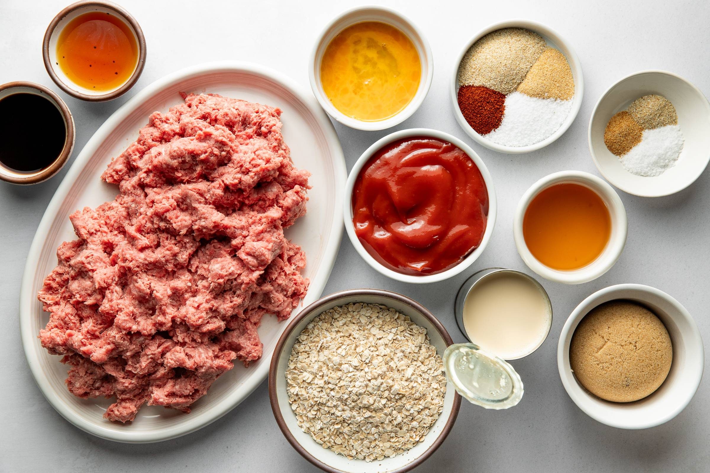 Ground beef, spices, oats, sauce, and other ingredients for BBQ meatballs.